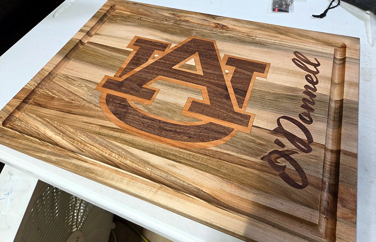 Maple cutting board with a walnut and cherry inlay and a script name