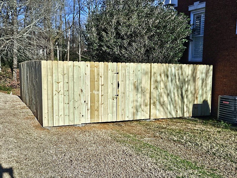 Wood privacy fence with a walk gate beside a brick house